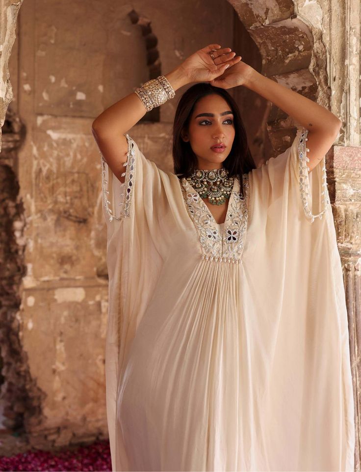 Introducing a stunning full-length draped kaftan, adorned with intricate embellishments on the neckline and sleeves. This statement piece exudes elegance and sophistication, offering both comfort and style. Perfect for adding a touch of luxury to your wardrobe, whether lounging at home or attending special occasions. Elegant V-neck Kurta For Festive Occasions, Silk Designer Dress With Draped Sleeves, Designer Silk Dress With Draped Sleeves, Silk Dress With Draped Sleeves For Designer Wear, Bollywood Style Embellished Georgette Kaftan, Embellished Georgette Kaftan With Traditional Drape, Bohemian Georgette Kurta With Sheer Dupatta, Festive Georgette Kurta With Embroidered Neckline, Bohemian Georgette Dress With Cape Sleeves