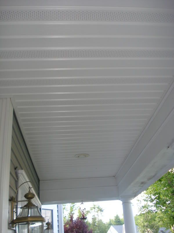 the porch is covered with white perfored roofing and has a lantern hanging from it