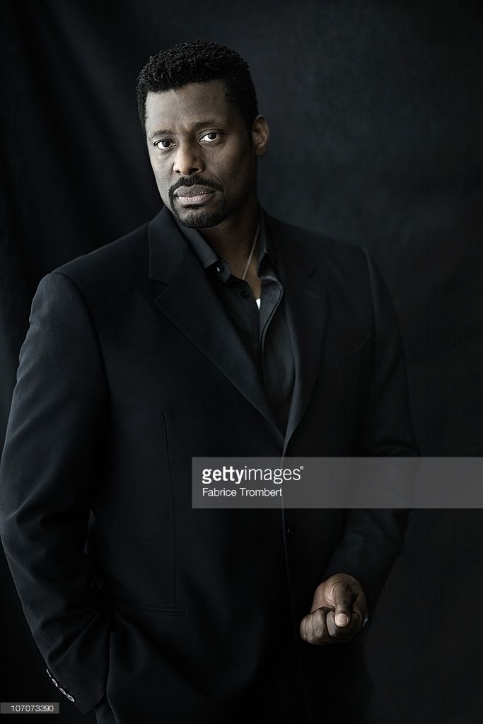 a man in a black suit posing for the camera