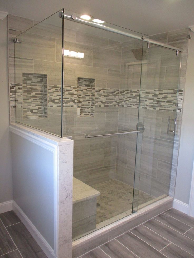 a walk in shower sitting next to a tiled wall