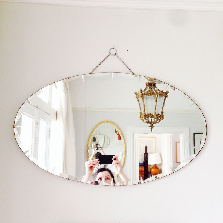 a woman taking a selfie in front of a mirror with a chandelier hanging from the ceiling