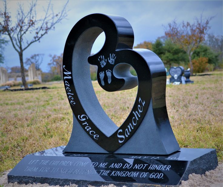 a memorial in the middle of a field with a heart shaped plaque on it's base