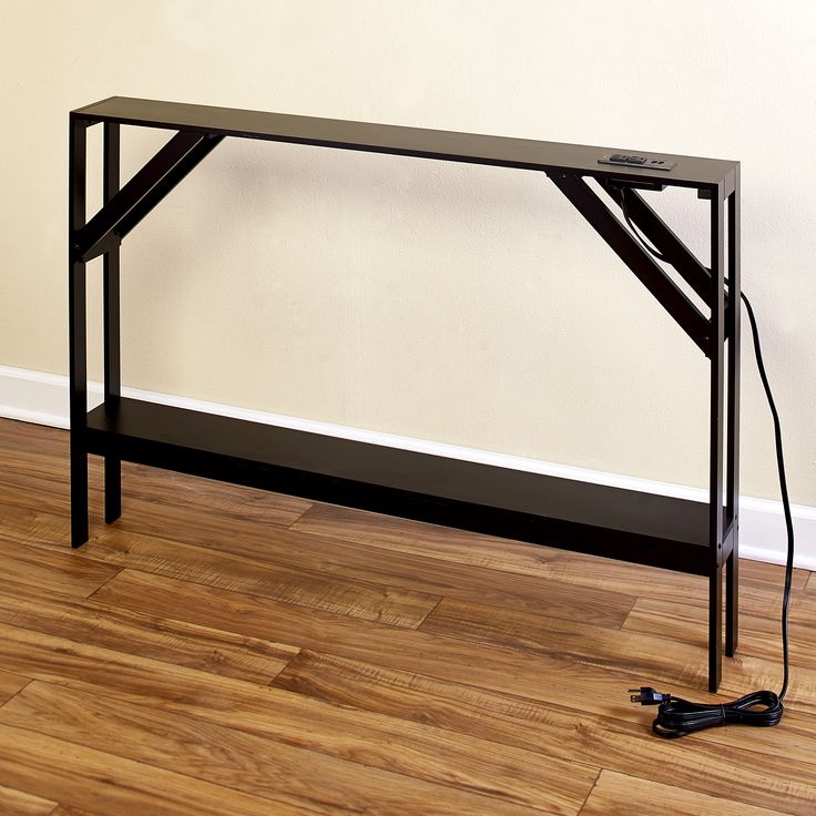 a black table sitting on top of a hard wood floor next to a white wall