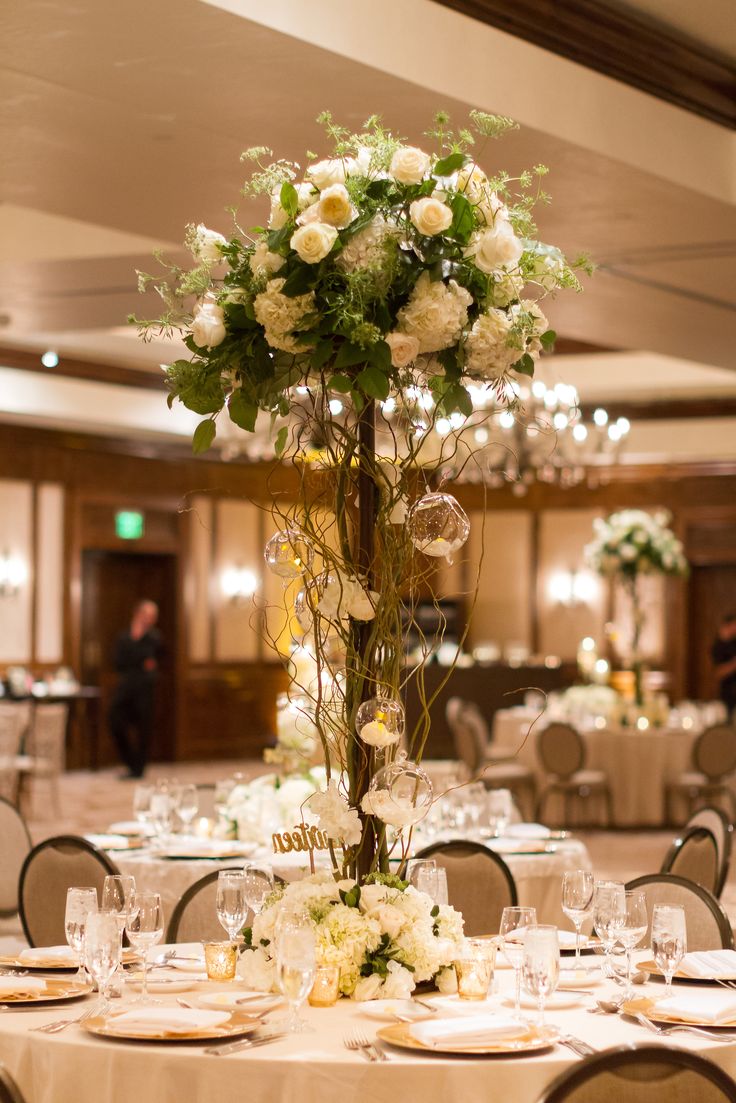 a tall vase filled with white flowers sitting on top of a table covered in plates