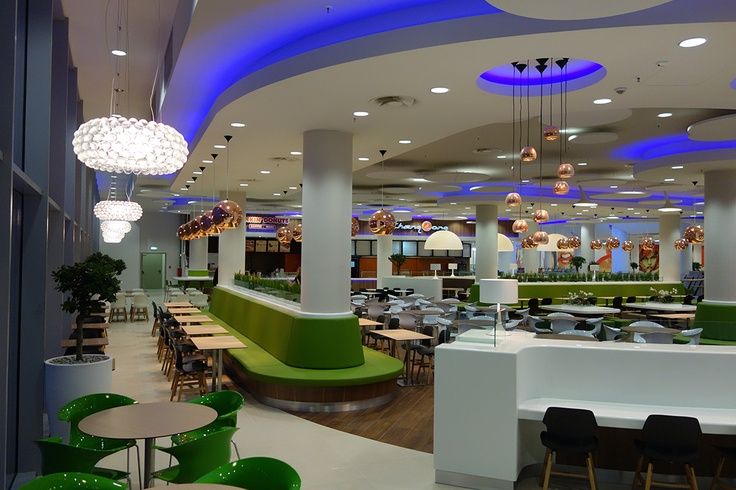 the interior of a restaurant with green and white tables, chairs, and lights hanging from the ceiling