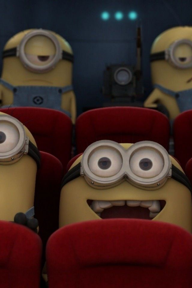 two minion characters sitting in the middle of a movie theater with their eyes closed