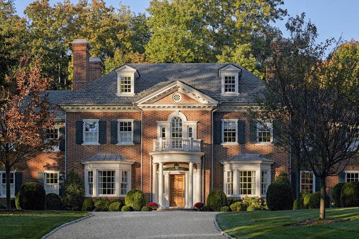 a large red brick house with white trim and black shutters on the front door