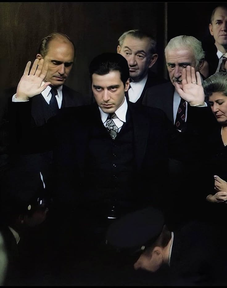 a group of men in suits and ties standing next to each other with their hands on their head