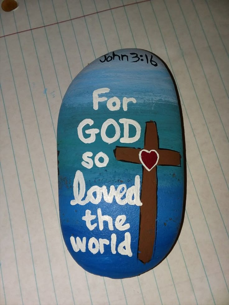 a painted rock with the words for god so loved the world and a cross on it