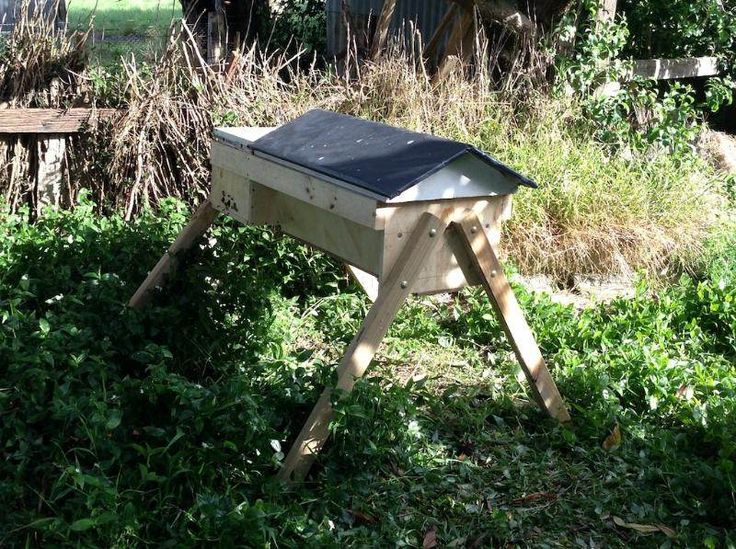 a wooden bird house in the middle of some bushes and trees with a black roof