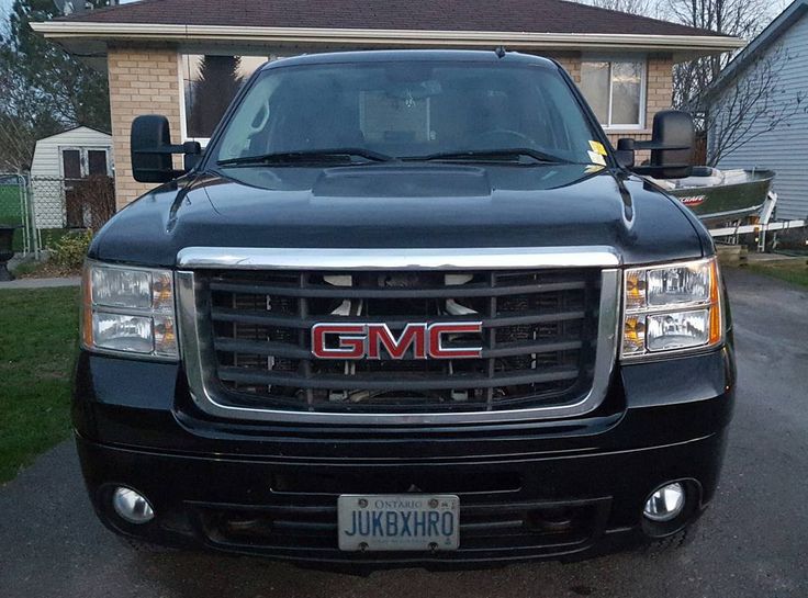 the front end of a black gmc truck parked in front of a small house