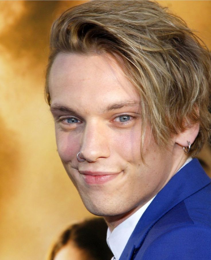 a close up of a person wearing a blue suit and tie with an earring