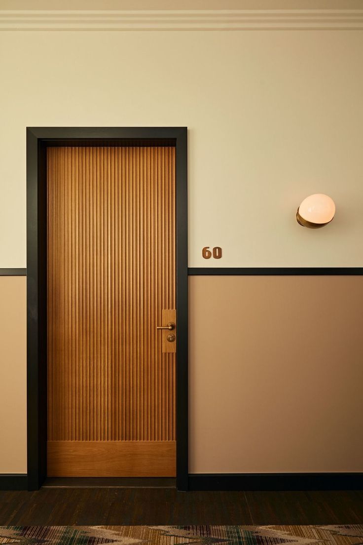 an empty room with a wooden door and two lamps on the wall next to it