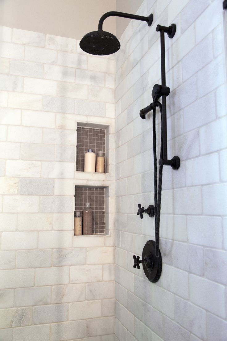 a bathroom with white brick walls and black shower faucet next to the toilet