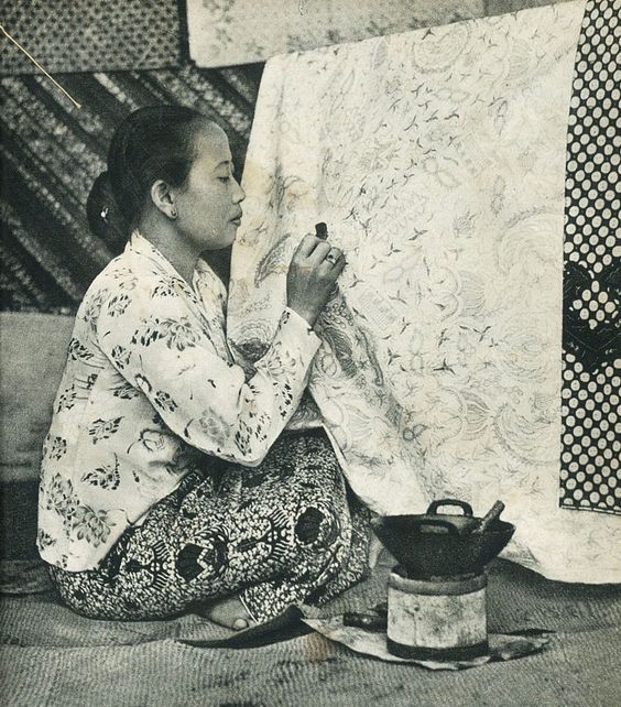 a woman sitting on the ground working on an art piece