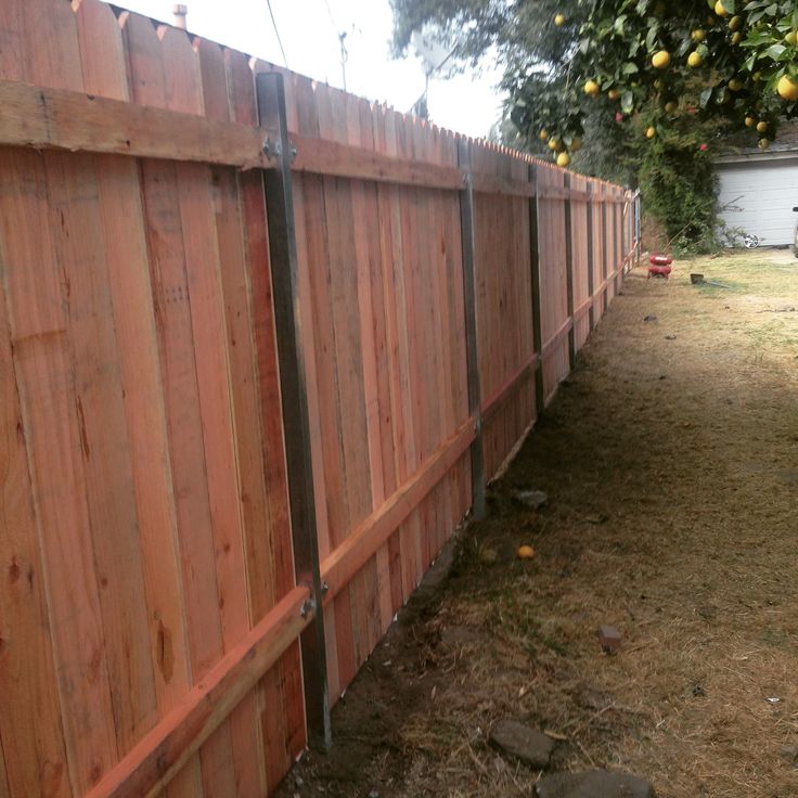 a wooden fence in the yard next to an apple tree with lots of fruit on it