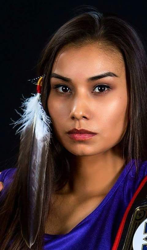 a beautiful young woman holding a feather in her right hand and looking at the camera