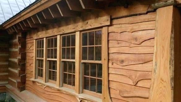 an old log cabin with wood siding and windows