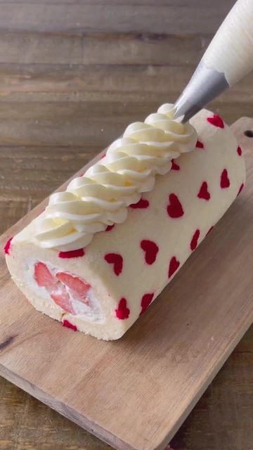 a piece of cake that has been decorated with hearts and icing on a cutting board