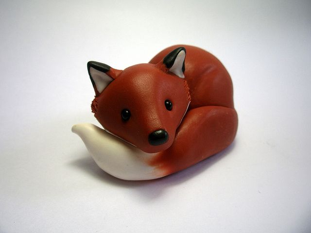 a small red fox figurine sitting on top of a white banana shaped object