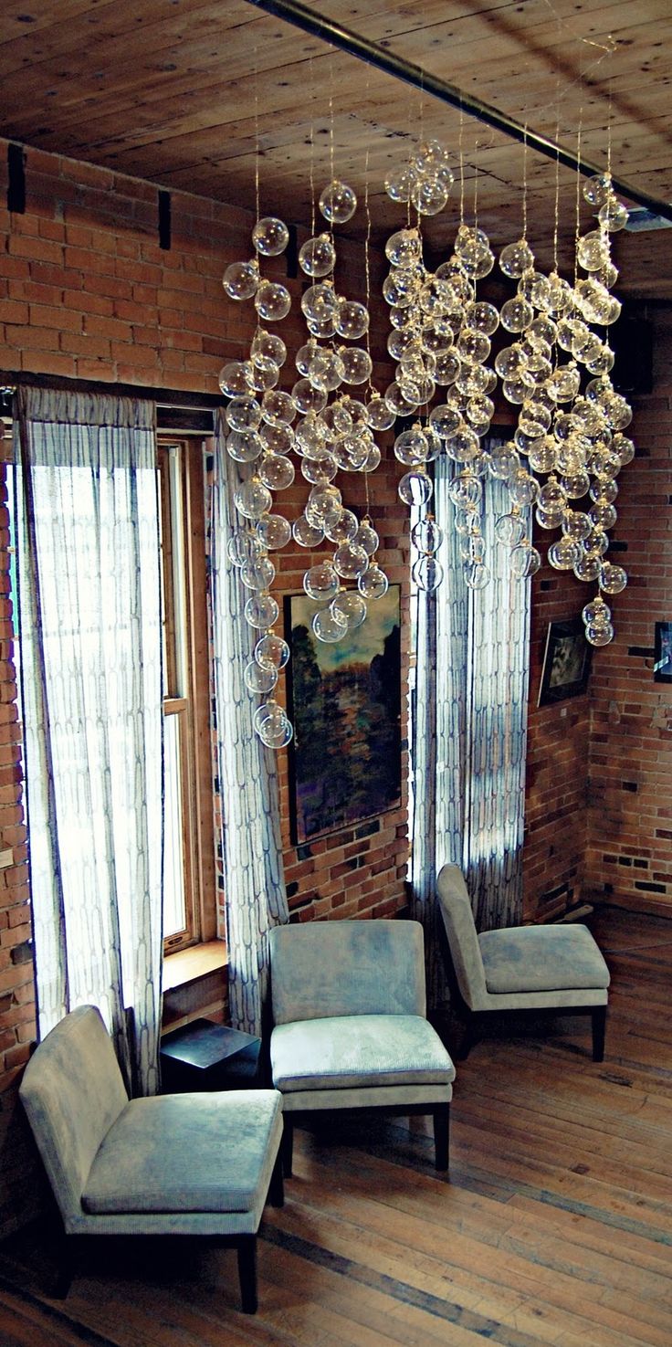 a living room filled with furniture and chandelier hanging from the ceiling next to windows