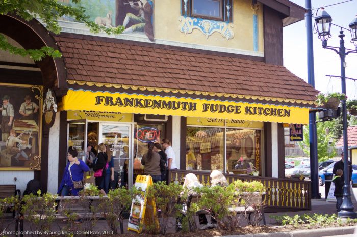 people are standing in front of a store called franklin fudge kitchen on the corner of a street