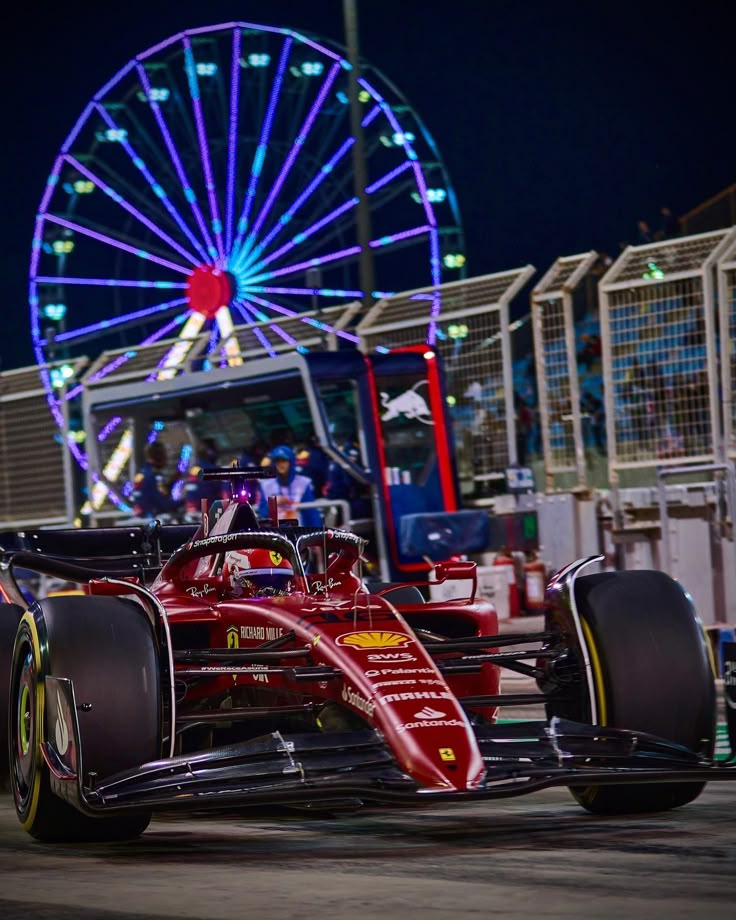 a red race car driving past a ferris wheel