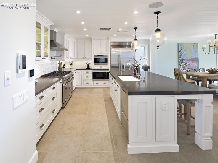 a large kitchen with white cabinets and black counter tops, along with an island in the middle