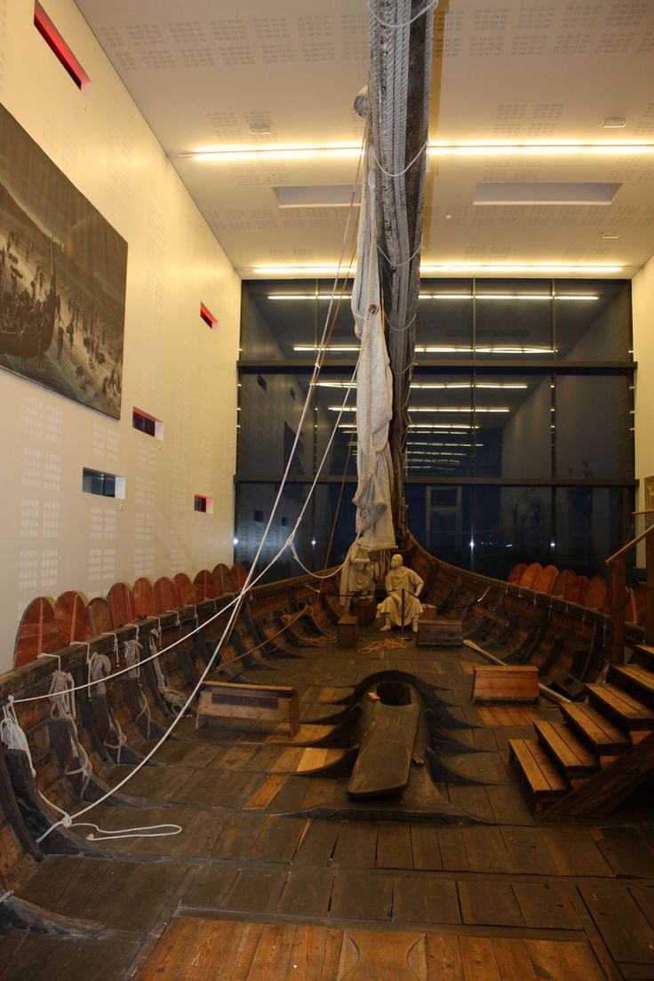 an old wooden boat is sitting in the middle of a room with chairs around it