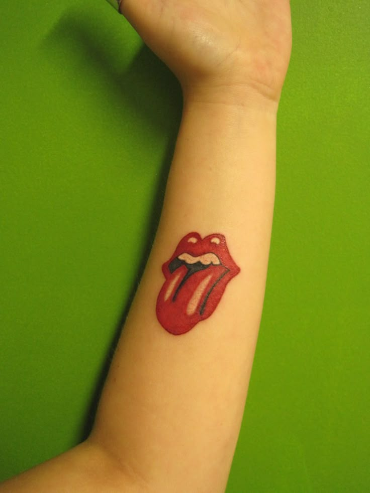 a woman's arm with a tattoo on it that has the rolling stones painted on it