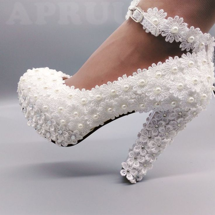 a woman's white high heeled shoes with pearls