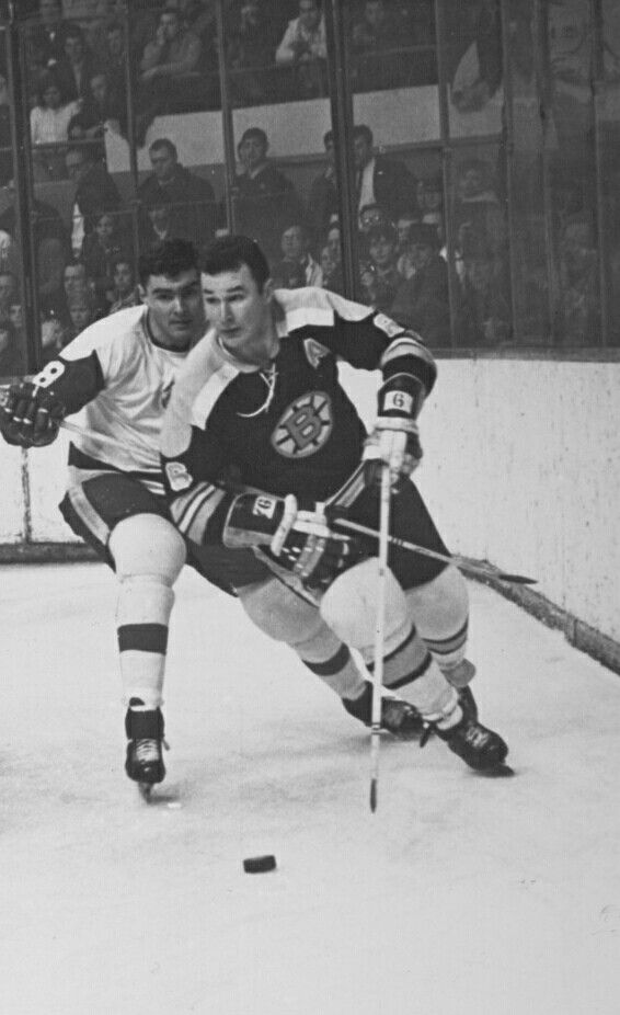 two men are playing hockey on an ice rink while people watch from the sidelines