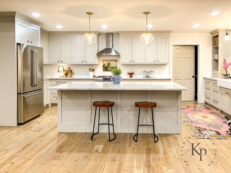 a large kitchen with two stools in front of the center island and an area rug on the floor