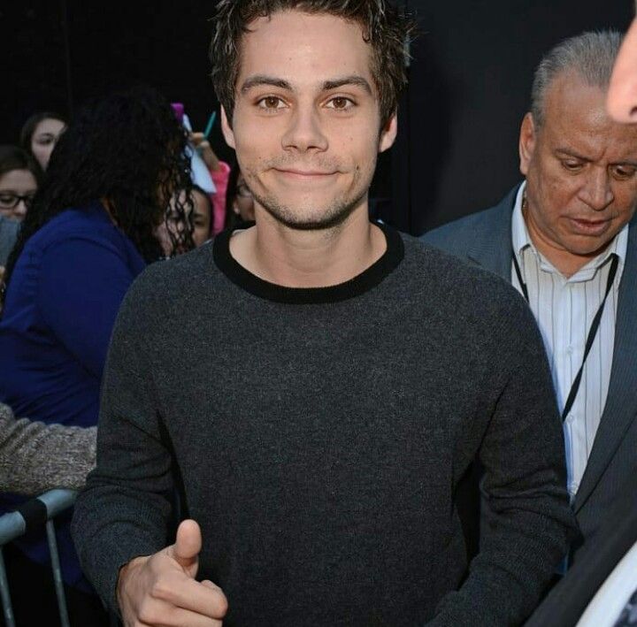 a man is standing in front of a crowd and giving the thumbs up sign with his right hand