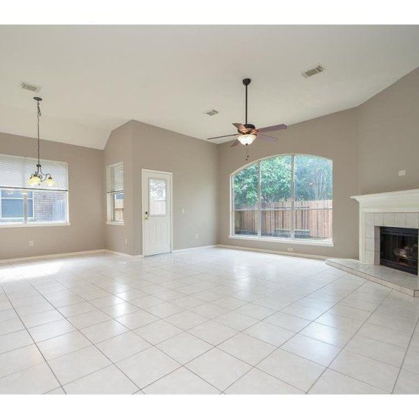 an empty living room with tile flooring and two windows in the middle of it