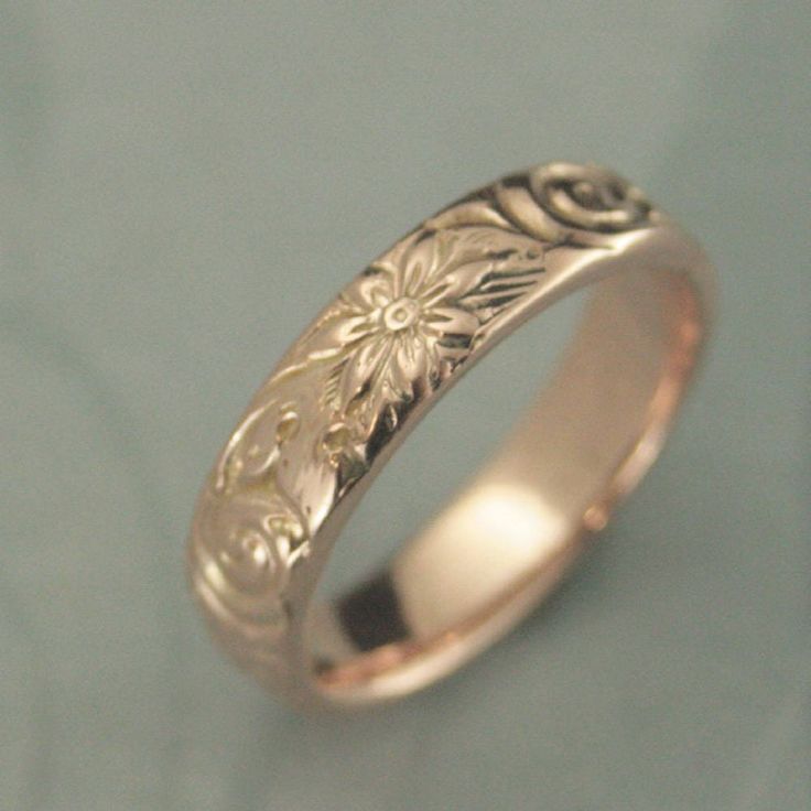 a wedding ring with an intricate design on the outside and inside, sitting on a blue surface