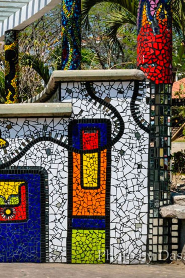 a colorfully painted building sitting next to a metal fence and palm tree in the background