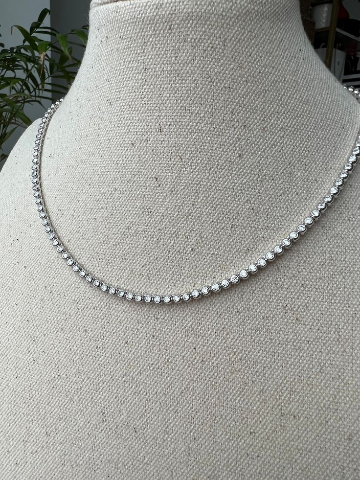 "Adorn yourself with this beautiful bezel round created diamond necklace. Set in sterling silver or gold tone, this necklace features a glamorous 3mm or 4mm 12.98/22.25 TCW diamond set in bezel settings. This sophisticated necklace adds an elegant finishing touch to every outfit. This exquisite necklace is available in three different color tones (silver, yellow gold tone, rose gold tone - please select). Please select the length and color tones above. You will receive ONE necklace with every or Silver Tennis Necklace With Round Diamond Cut, Silver Tennis Necklace With Diamond Cut, Silver Dainty Tennis Necklace, Dazzling Silver Single Strand Jewelry, Silver Sterling Single Strand Tennis Necklace, Silver Cubic Zirconia Single Strand Tennis Necklace, Silver Single Strand Cubic Zirconia Tennis Necklace, Silver Single Strand Tennis Necklace, Dainty Silver Tennis Necklace