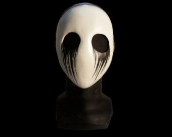 a white mask with black eyes on a black background