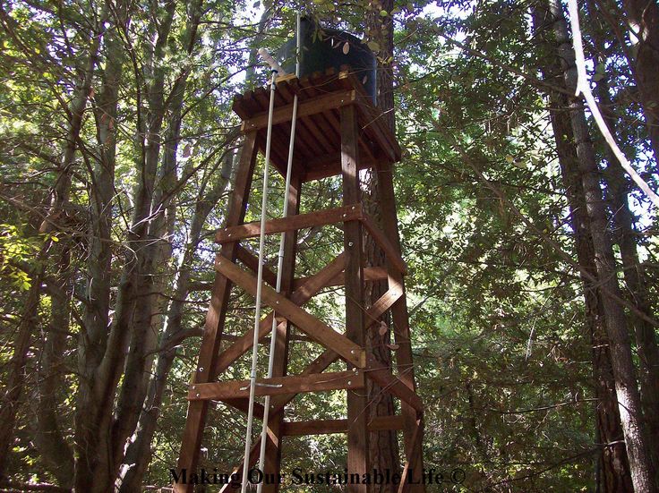 a tall wooden tower in the middle of a forest with ropes hanging from it's sides