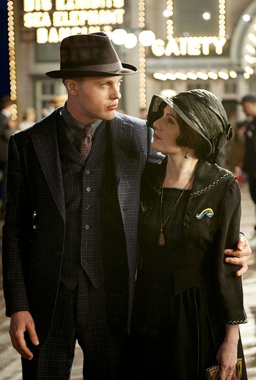 a man and woman standing next to each other in front of a building at night