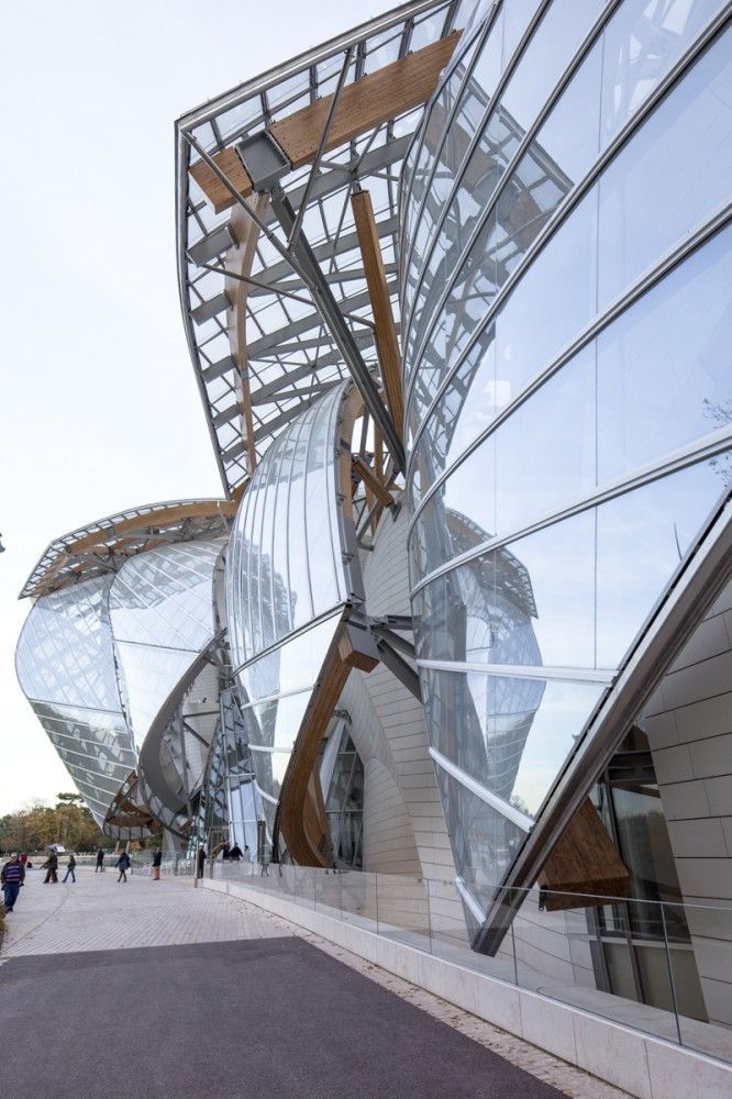 a large building that has some glass on it's side and people walking around