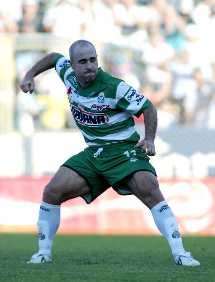 a man in green and white uniform kicking a soccer ball on the field during a game