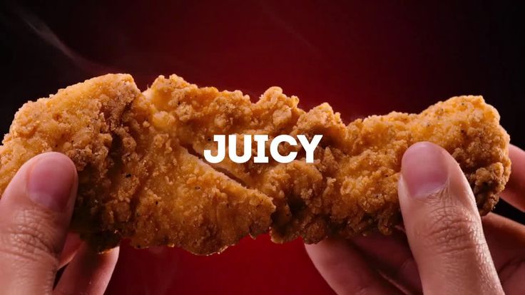 two hands holding up a fried chicken nugget with the word juicy written on it