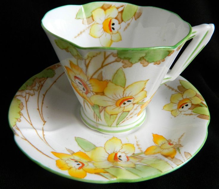 a tea cup and saucer with yellow flowers on the bottom, sitting on a black background