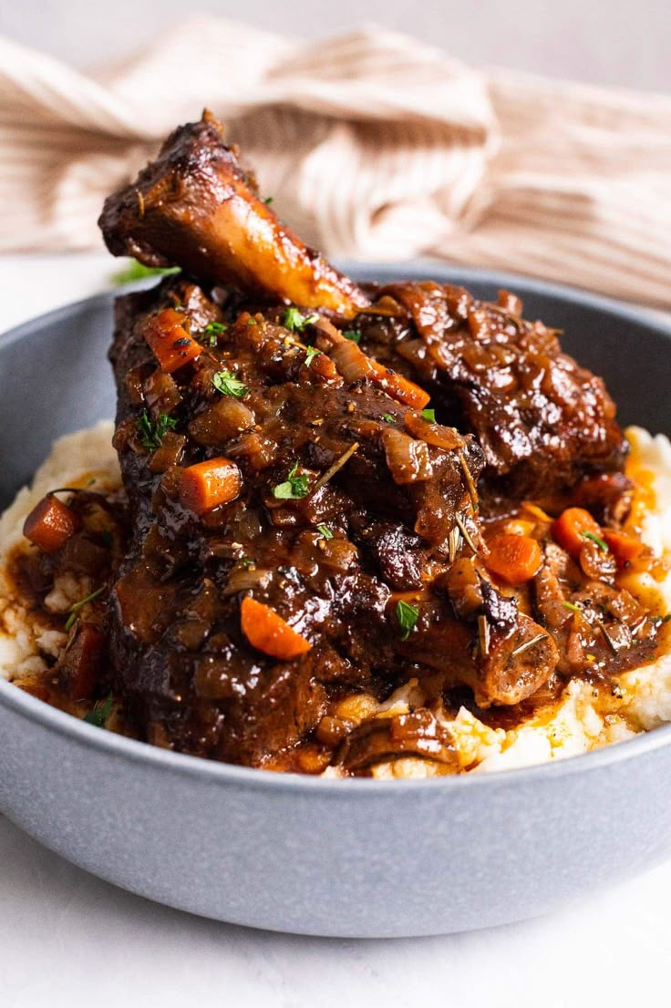 a bowl filled with meat and vegetables on top of mashed potatoes