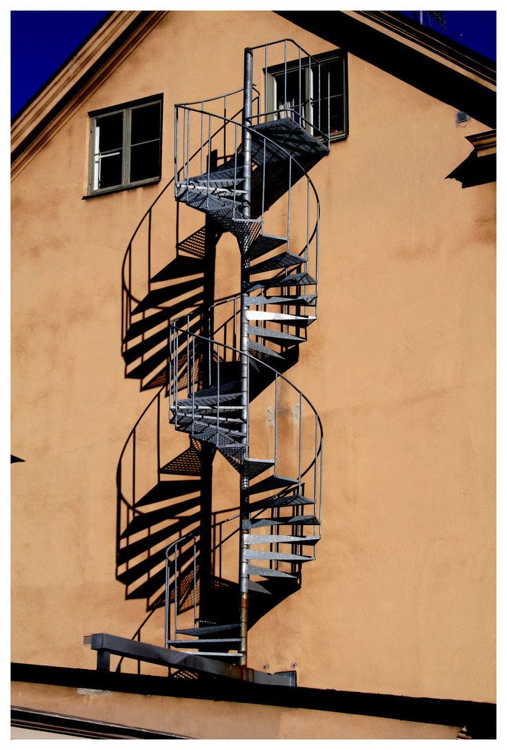 a tall metal spiral staircase on the side of a building