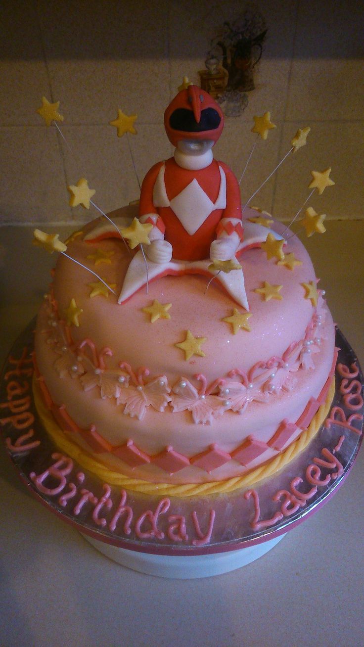 a pink birthday cake decorated with stars and a figure on top