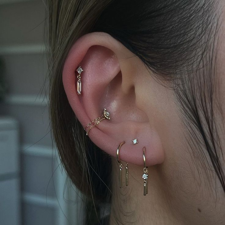 a close up of a person's ear with three different piercings on it