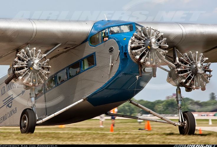 an airplane that is sitting in the grass with wheels on it's sides and two people inside